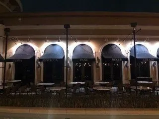 A restaurant with tables and chairs outside at night