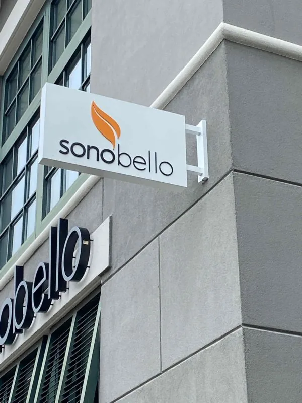 A Sono Bello blade sign mounted on the corner of a building
