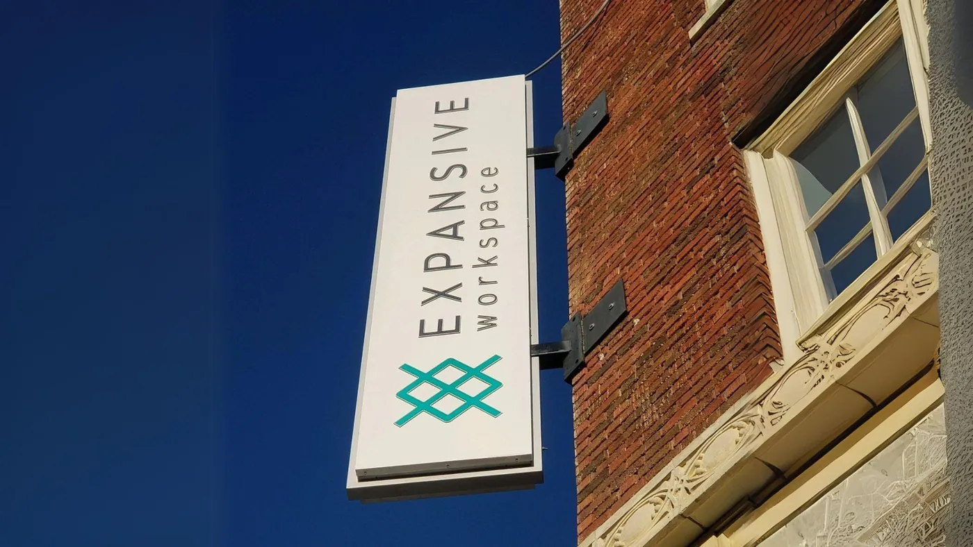 Expansive Workspace blade sign projecting from a brick building