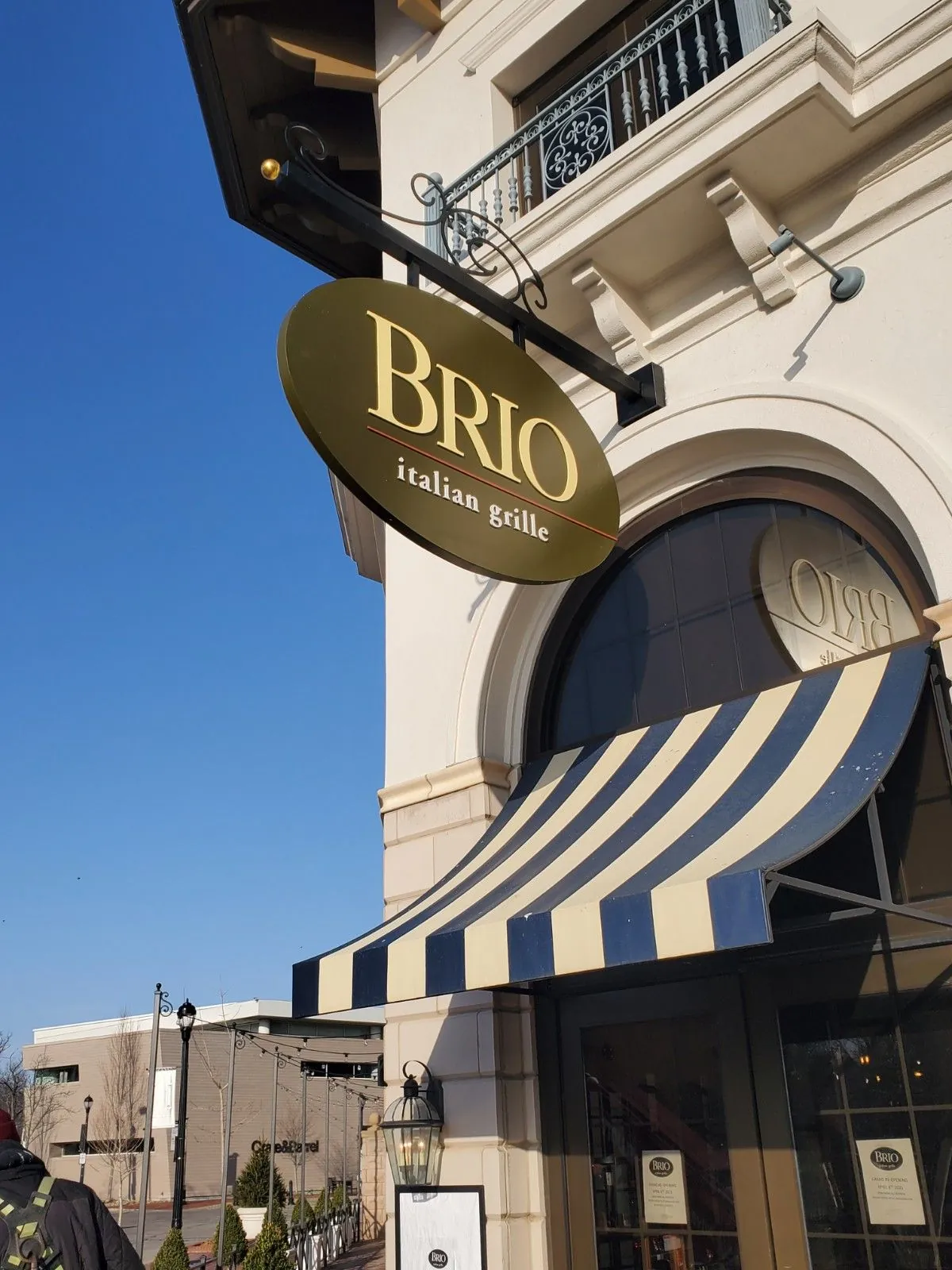 A Brio Italian Grille oval blade sign on a decorative bracket