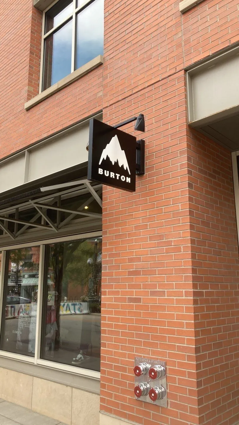 A Burton blade sign projecting from a brick storefront