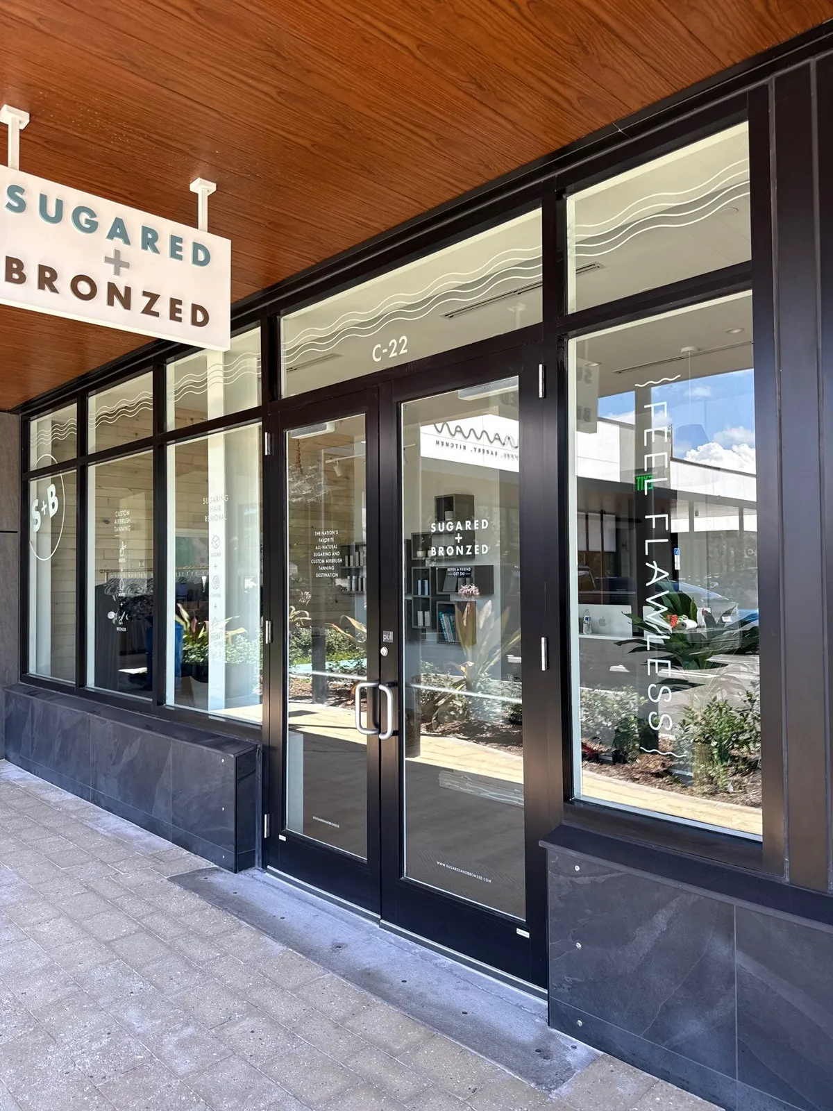 A Sugared and Bronzed blade sign over the sidewalk
