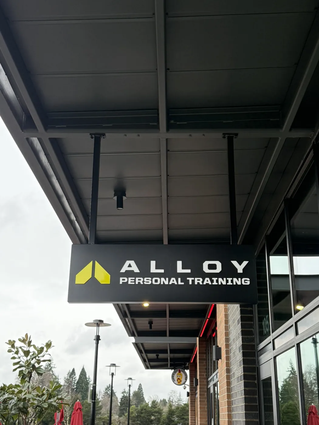 An Alloy Personal Training blade sign hanging beneath a storefront canopy