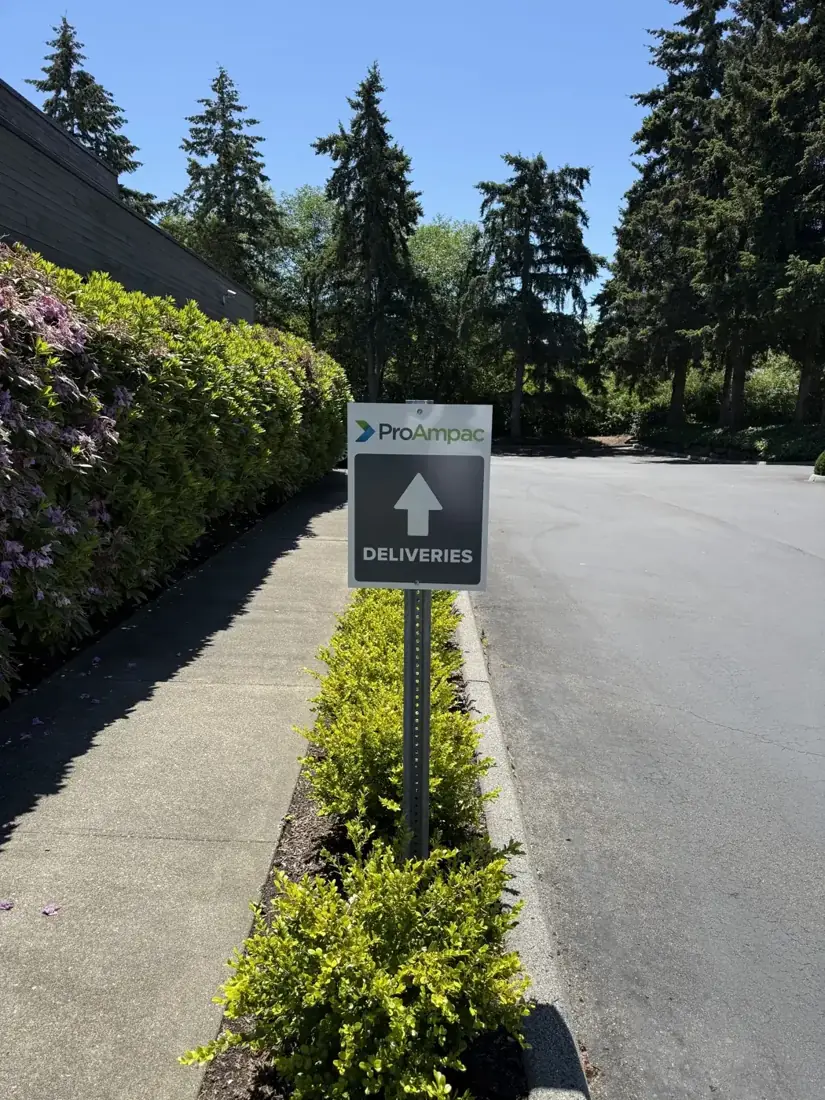 A ProAmpac deliveries directional sign on a post beside the driveway